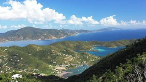 Eine Küstenlandschaft mit Blick auf das Meer, Hügel und verstreute Gebäude.