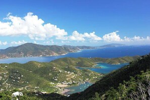 A coastal landscape with a view of the sea, hills, and scattered buildings.