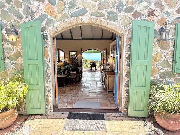 A stone building with an open archway leading to a room with furniture and a view.