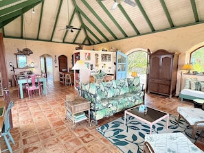 A spacious living area with a high ceiling, a sofa, a coffee table, and a dining table with chairs. - Discover Orchid Knoll – a Caribbean island retreat offering breathtaking views, a refreshing pool, and complete privacy! Don’t miss out on this incredible opportunity to unwind in a tropical setting. (Bordeaux Mountain)