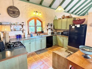 A kitchen with green cabinets, a black refrigerator, and a wooden island. - Discover Orchid Knoll – a Caribbean island retreat offering breathtaking views, a refreshing pool, and complete privacy! Don’t miss out on this incredible opportunity to unwind in a tropical setting. (Bordeaux Mountain)