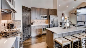 A modern kitchen with a central island, stainless steel appliances, and wooden cabinetry. - Keystone 4BR Townhome at River Run Base - Prices lowered for open dates! (Keystone)