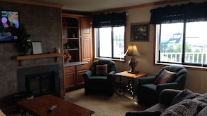 A living room with a fireplace, a television, and a view of the outside. - Ski-in/Ski-out, Penthouse Unit w/ Awesome Views, Walk to Village! (Snowshoe)