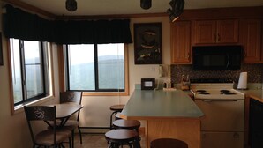 A kitchen with a large island, bar stools, a microwave, and a stove. There are windows with a view of mountains. - Ski-in/Ski-out, Penthouse Unit w/ Awesome Views, Walk to Village! (Snowshoe)