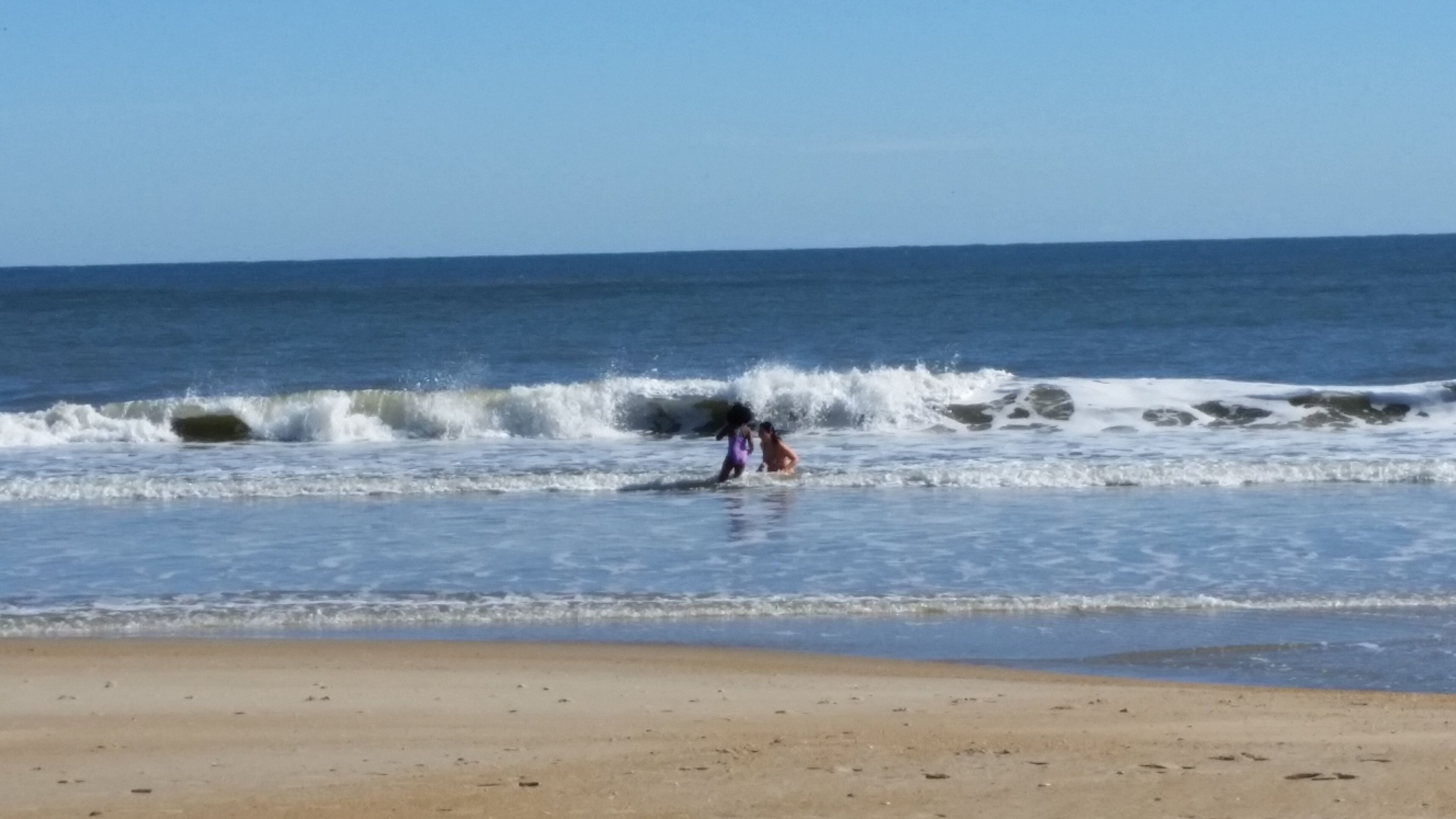 A beach with waves and a clear sky.