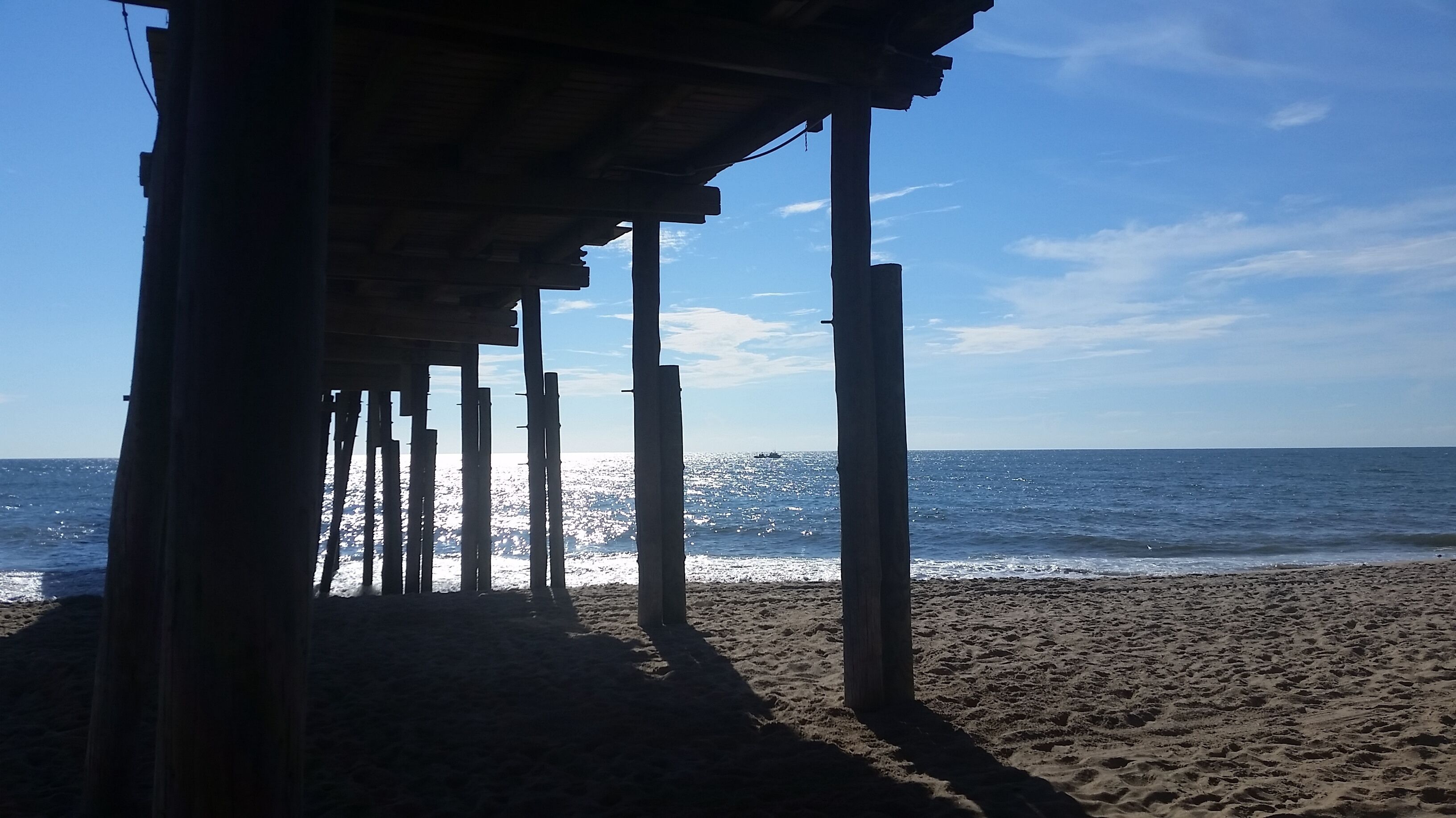 A beach with wooden pillars and a clear view of the ocean.