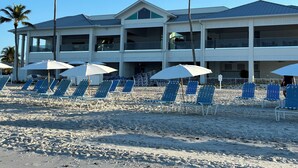 Un hôtel situé en bord de mer, doté de nombreux balcons, de chaises longues et de parasols.