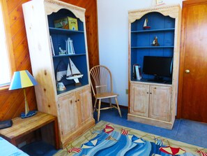A room with wooden cabinets, a television, a chair, and a patterned rug. - Snorkel A Shipwreck...Two Ships Are On The Bottom Just Off The Beach!! (Kill Devil Hills)