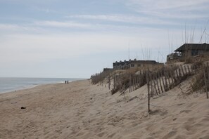 A sandy beach with a wooden fence and buildings in the background. - Snorkel A Shipwreck...Two Ships Are On The Bottom Just Off The Beach!! (Kill Devil Hills)