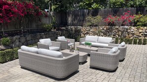 A patio with wicker furniture, a stone wall, and a wooden fence. - Spacious home in Carmel: one mile to downtown.  (Carmel-By-The-Sea)