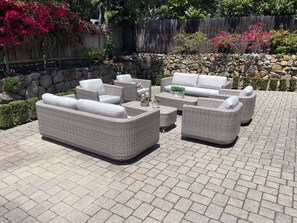 A patio with wicker furniture, a stone wall, and a wooden fence.