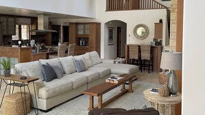 A spacious living area with a high ceiling, a kitchen in the background, and a staircase leading to an upper level. - Spacious home in Carmel: one mile to downtown.  (Carmel-By-The-Sea)