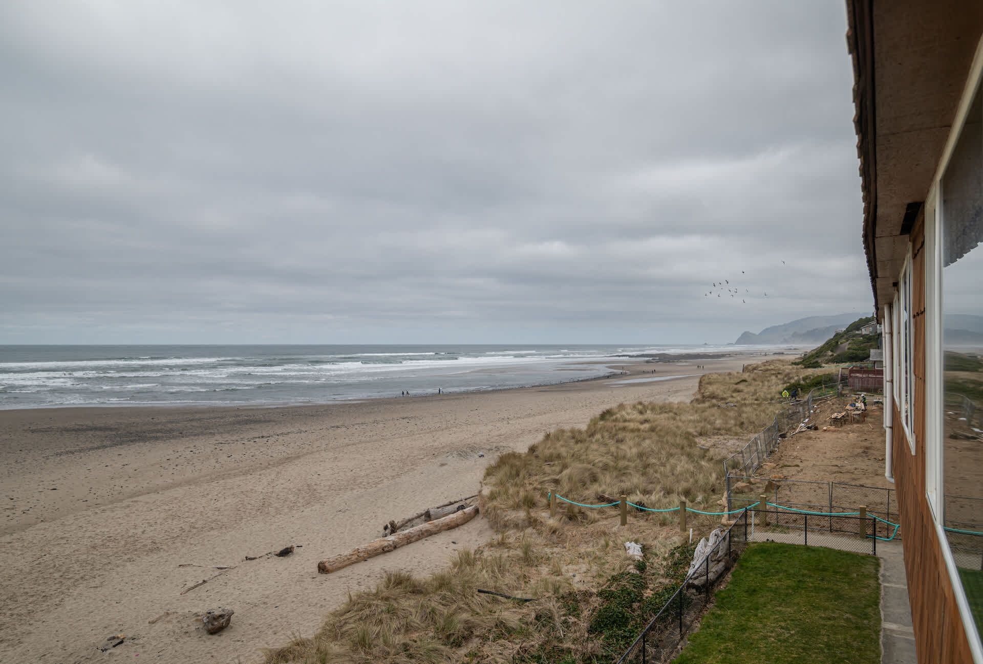 A beach with a view of the ocean and a building with a window overlooking the beach.