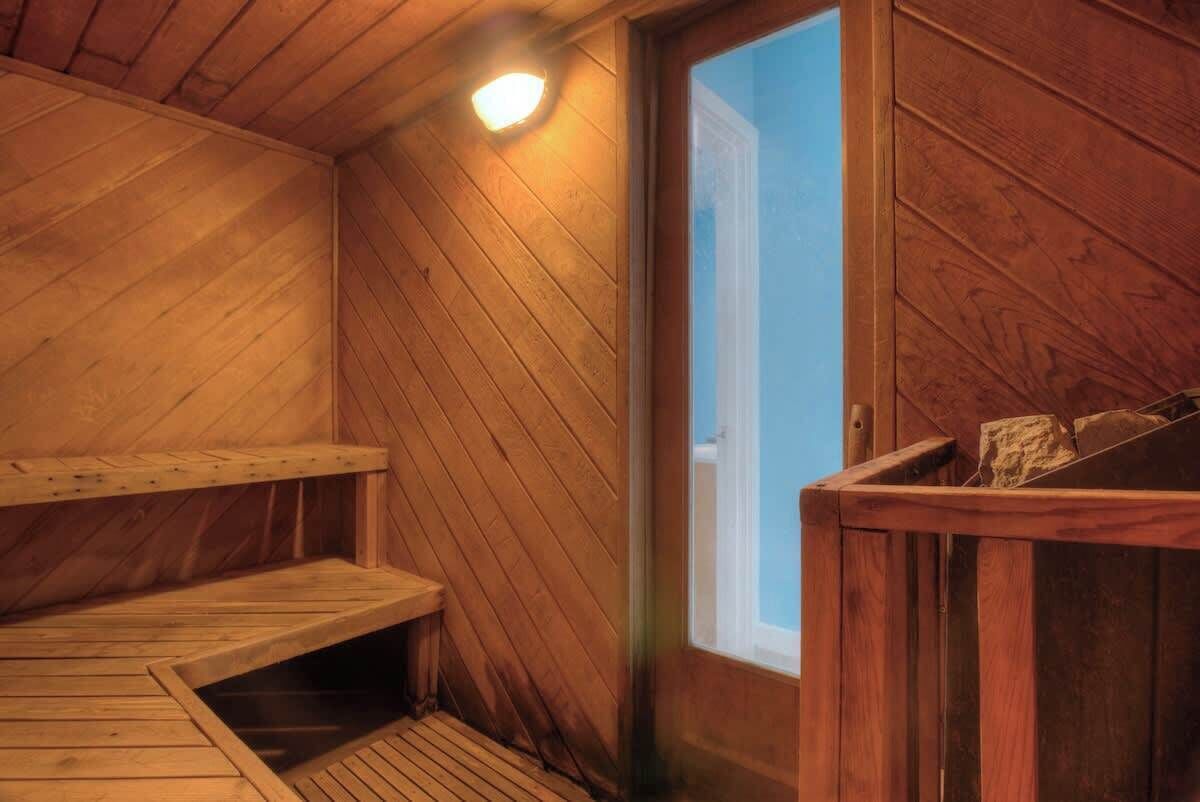 Un sauna en bois avec un banc, une petite fenêtre et un luminaire.