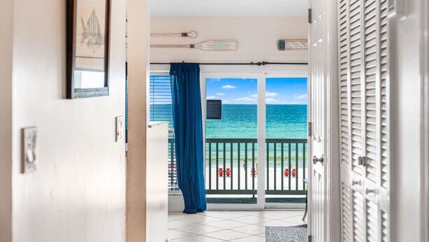 A hotel room with a view of the ocean, a balcony with a blue curtain, and a door with a white shutter. - From sunrise surf to sunset sips at Beach Life /Gulf Front, Driect Access to Beach from Balcony (Santa Rosa Beach)