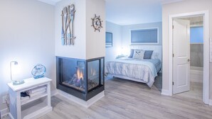 A bedroom with a fireplace, a bed with a blue and white bedspread, and a walk-in closet.