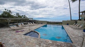 Un espace piscine avec des chaises longues et vue sur l’océan.