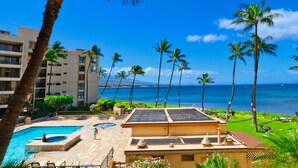 A resort with a swimming pool, palm trees, and a view of the ocean. - Oceanfront Condo at Sugar Beach Resort- Stunning Sunsets and Beach Front (Kihei)