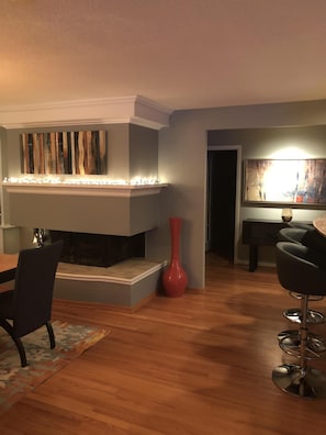Una sala de estar moderna con chimenea, una mesa de comedor y un jarrón rojo.
