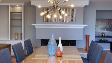 A dining area with a long rectangular table, blue upholstered chairs, and a modern chandelier with multiple light bulbs.