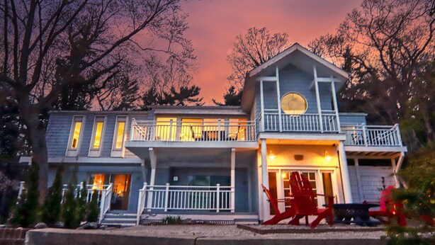 A two-story house with a balcony, a front porch, and a circular window on the second floor.