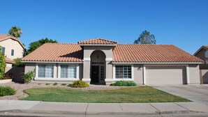 A two-story house with a tiled roof, a front garage, and a well-maintained lawn. - Spacious & Spotless Family Retreat -Single-Story Comfort – Close to Everything! (Mesa)