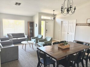 A living room with a sofa, chairs, a dining table, and a chandelier.
