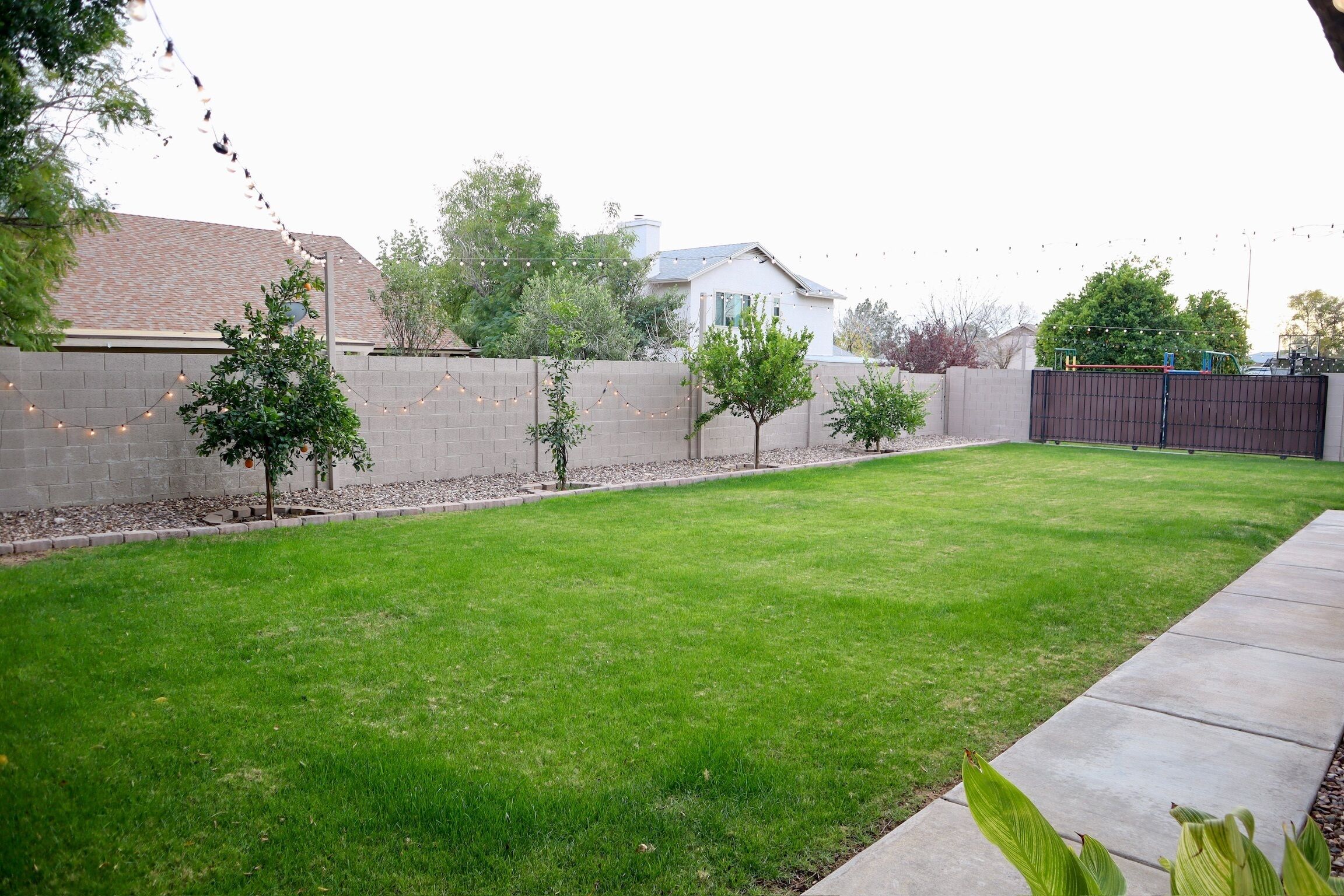 A well-maintained backyard with a neatly trimmed lawn, a brick wall, and a wooden fence.