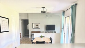 A modern kitchen with wooden cabinets, a built-in dishwasher, and a dining area with a table and chairs. - Spacious & Spotless Family Retreat -Single-Story Comfort – Close to Everything! (Mesa)