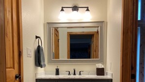 A bathroom with a large mirror, dark cabinets, and a light-colored countertop. - CREEKSIDE AND MOUNTAIN VIEW! Walk to Main St Frisco, Skiing, Pool, Trails (Frisco)