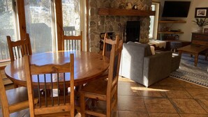 A cozy living room with a stone fireplace, wooden furniture, and a television mounted on the wall. - CREEKSIDE AND MOUNTAIN VIEW! Walk to Main St Frisco, Skiing, Pool, Trails (Frisco)