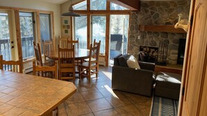 A spacious living area with a stone fireplace, wooden furniture, and large windows. - CREEKSIDE AND MOUNTAIN VIEW! Walk to Main St Frisco, Skiing, Pool, Trails (Frisco)