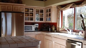 A kitchen with wooden cabinets, a stainless steel refrigerator, a microwave, and a dishwasher. - Dragonfly Ranch-Stunning Ocean View 320 Acre Ranch (Atascadero)