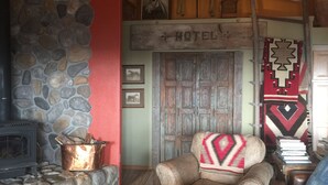 A rustic interior with a stone fireplace, a wooden door labeled 'HOTEL', and a traditional woven blanket. - Dragonfly Ranch-Stunning Ocean View 320 Acre Ranch (Atascadero)