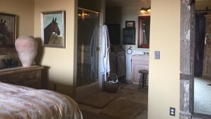 A bedroom with a bed, a large vase, and a painting of a horse. - Dragonfly Ranch-Stunning Ocean View 320 Acre Ranch (Atascadero)
