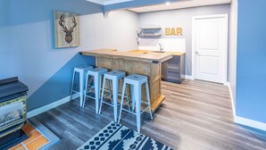 A modern kitchen with a wooden island, bar seating, and a mounted deer head artwork. - Mountain View 4BR Chalet with contactless entry - The Lake at Blue Mountains (Blue Mountains)
