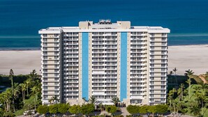 Un hôtel de grande hauteur doté de nombreux balcons, offrant une vue sur la plage et caractérisé par une bande bleue centrale.