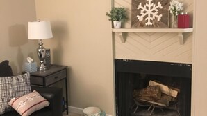 Un salon avec une cheminée, un canapé, une lampe et une table basse.