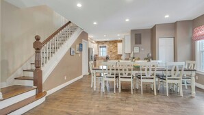 A spacious kitchen with a central island, white cabinetry, and a wooden staircase. - 22 Grover's Ocean, spacious 5 bedroom home with central AC, 1 block to beach! (Ocean Grove)