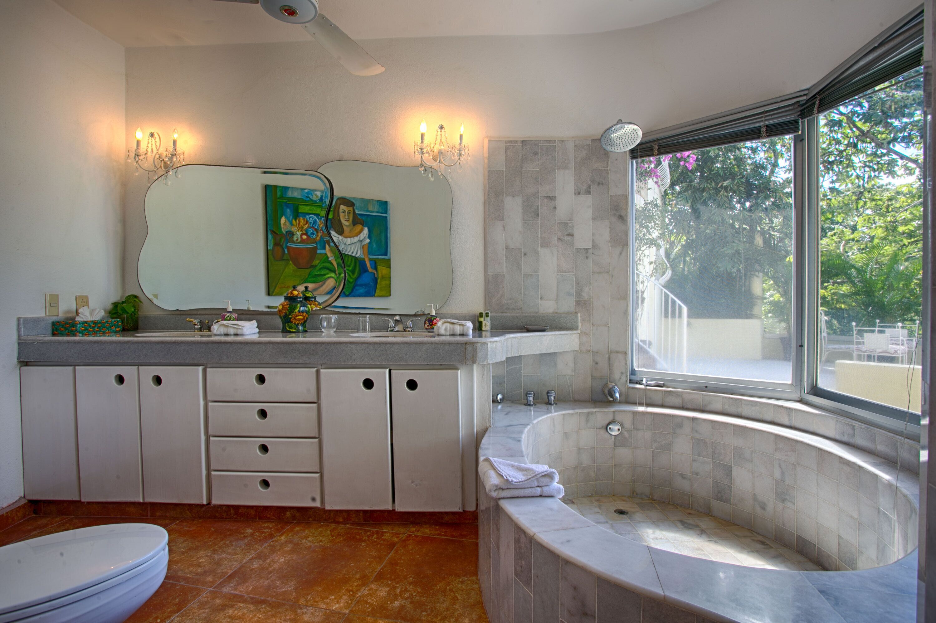 A bathroom with a large bathtub, a sink with a mirror, and a toilet.