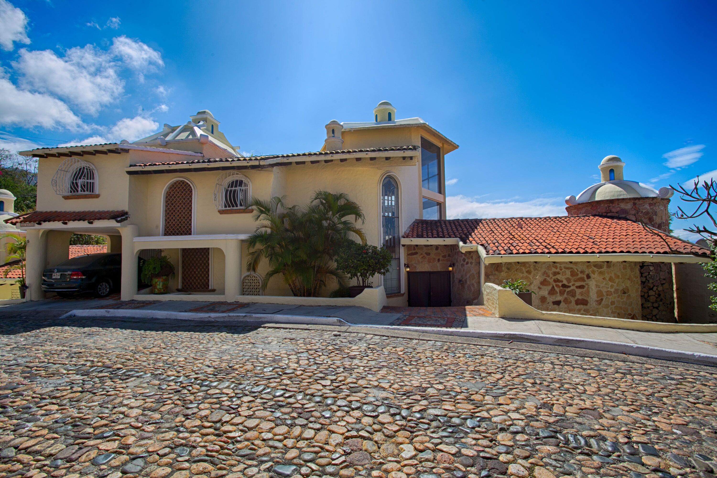 A two-story building with a stone facade, a red-tiled roof, and a dome structure.