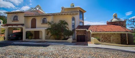 A two-story building with a stone facade, a red-tiled roof, and a dome structure.
