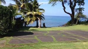 A well-maintained lawn with stone pathways leading to a body of water, surrounded by palm trees and other greenery. - Private Oceanfront Makena Retreat for 2, Maui County Permitted Short-Term Rental (Kihei)