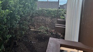 A balcony with a view of a rocky garden, palm trees, and the ocean. - Private Oceanfront Makena Retreat for 2, Maui County Permitted Short-Term Rental (Kihei)