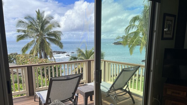 A balcony with a view of the ocean, palm trees, and a TV. - Private Oceanfront Makena Retreat for 2, Maui County Permitted Short-Term Rental (Kihei)