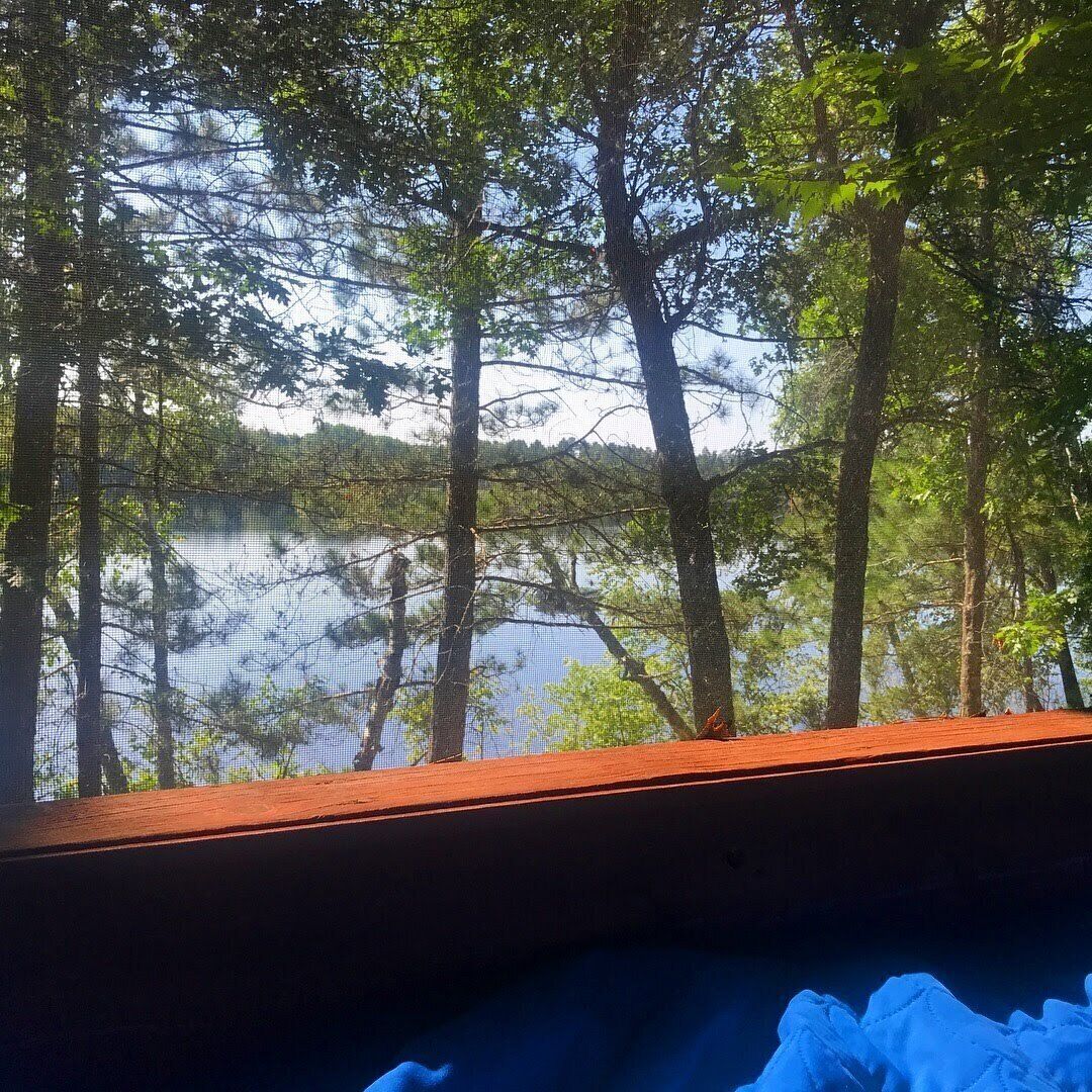 A view from a window overlooking a lake surrounded by trees.