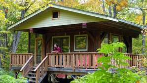 A wooden cabin with a porch, a set of stairs, and a window. - Mökki Hovland Hut - A Unique Glass Wall Timber Frame Nestled in a Maple Forest (East Cook)