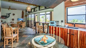 Una cucina moderna con mobili in legno, un'area pranzo con sedie in vimini e un'ampia finestra che offre vista sull'esterno.