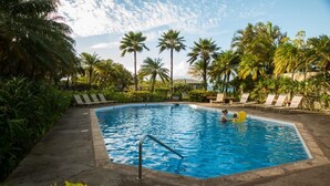 Una piscina con lettini e palme.