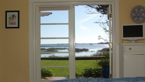 A bedroom with a large window overlooking a body of water, a television on a stand, and a framed picture on the wall. - An irresistable oceanfront vacation home in the heart of historic St Augustine! (St Augustine)